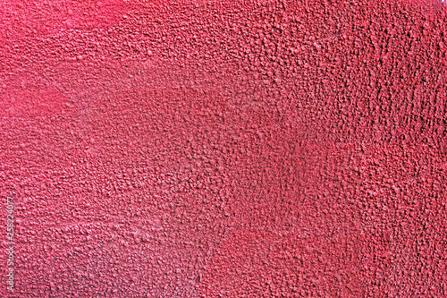 Texture of old red paint on a concrete wall a concrete wall. Chipped plaster on the wall weathered with cracks and scratches