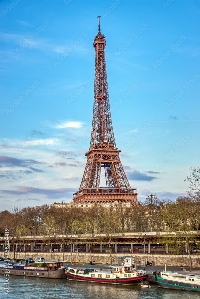 Fototapeta premium Paris, France: Eiffel tower in summer with Seine river and boats in foreground. Shoot at Golden hour.