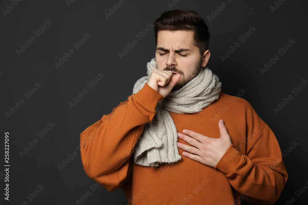Handsome young man coughing against dark background Handsome young man coughing against dark background