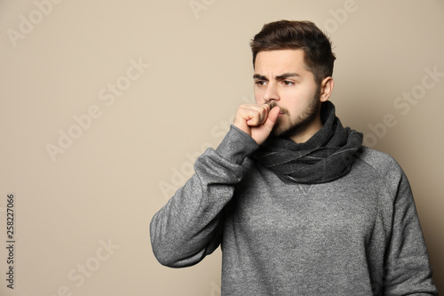 Handsome young man coughing against color background. Space for text © New Africa