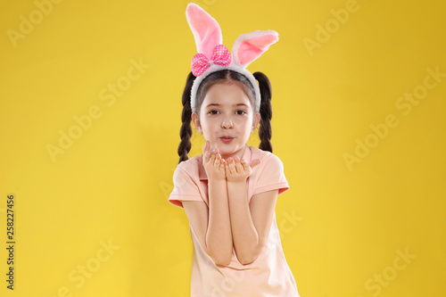 Portrait of little girl in Easter bunny ears headband on color background