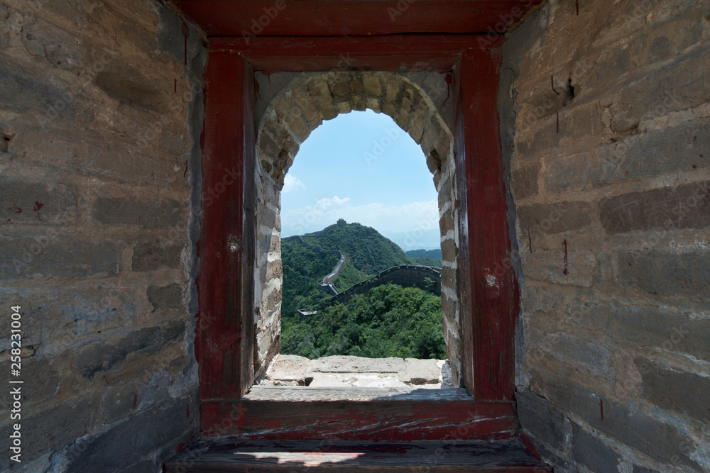 View through a brick window of a Fortress Guard Tower of Mutianyu, a section of the Great Wall of China during summer. Huairou District, Beijing, China