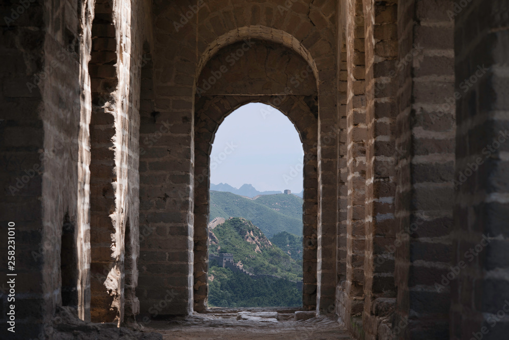 View through a brick window of a Fortress Guard Tower of Mutianyu, a section of the Great Wall of China during summer. Huairou District, Beijing, China