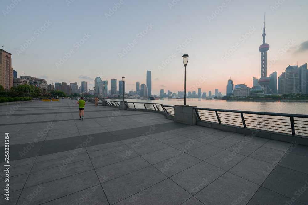 Shanghai, China - 08 27 2016: chinese people enjoy walking or running at The Bund early in the morning at sunrise. View of Pudong from The Bund in Shanghai, China