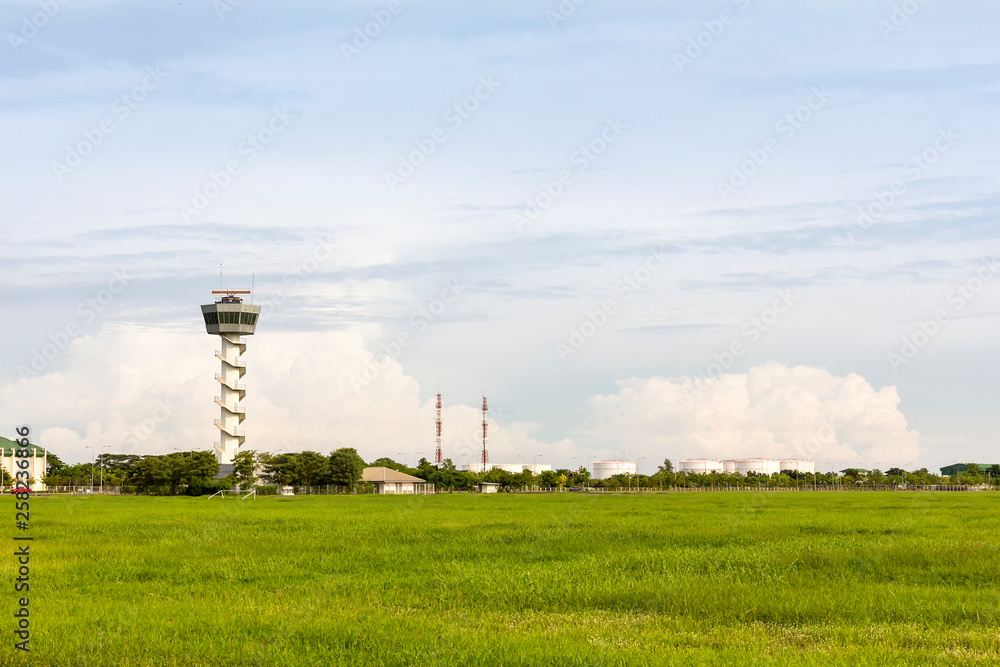 airport control tower for air traffic management with at green field near oil tank on cloudy sky background in evening airport control tower for air traffic management with at green field near oil tank on cloudy sky background in evening