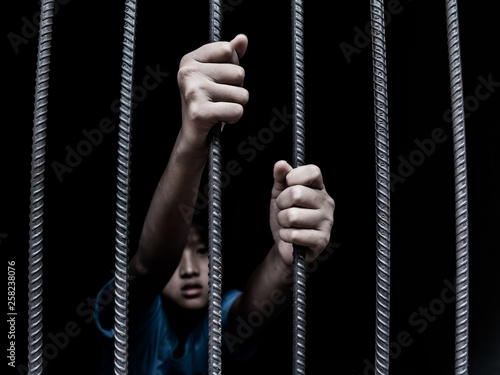 sad child holding a steel cage in old iron bar. children prison and prisoner concept © AungMyo