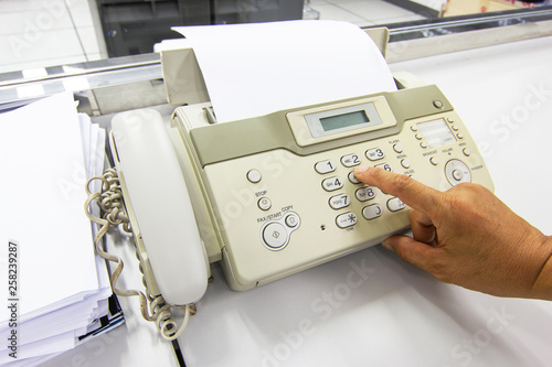 Hand man are using a fax machine send paper in the office Business concept 