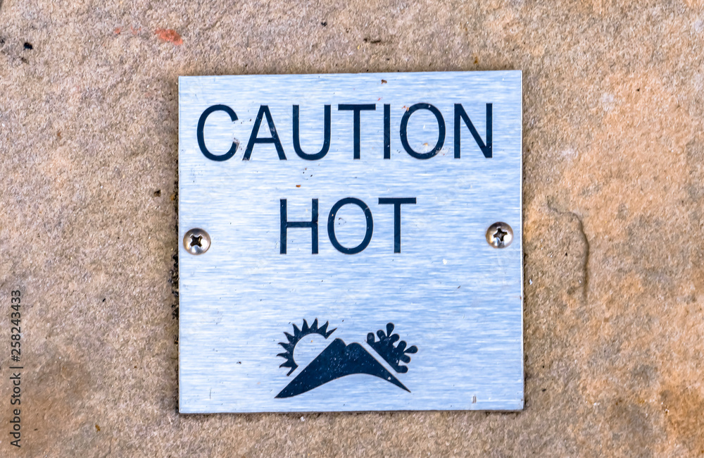 Obraz premium Caution Hot sign against a stone surface