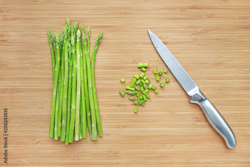 Fresh green asparagus and sliced on wooden board background with sharp knife. Fresh green asparagus and sliced on wooden board background with sharp knife.