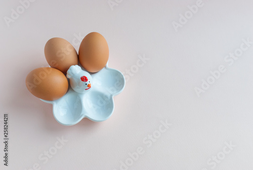 White ceramic egg holder with egg on pink soft background. Ceramic chicken. Top view