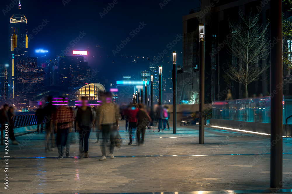Obraz premium Hong Kong cityscape at night. Tourists walking on the waterfront