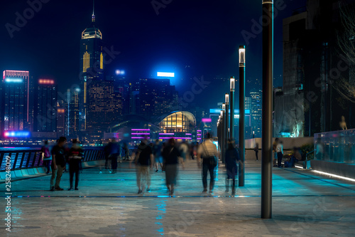 Hong Kong cityscape at night. Tourists walking on the waterfront