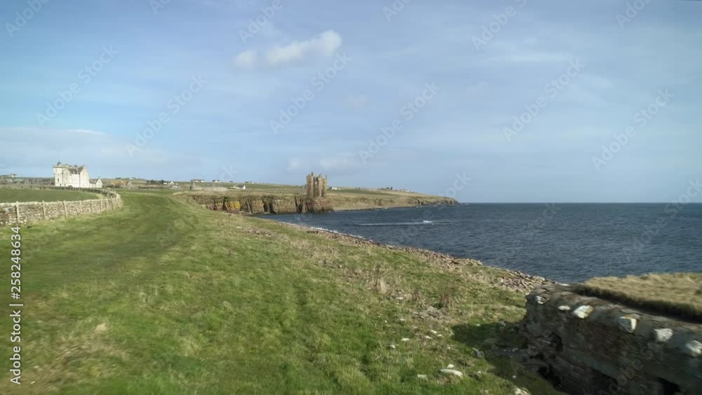 Aerial shot moving across the coastline towards Keiss Castle with an old WW2 bunker in the foreground on a sunny day, Caithness, Scotland Aerial shot moving across the coastline towards Keiss Castle with an old WW2 bunker in the foreground on a sunny day, Caithness, Scotland