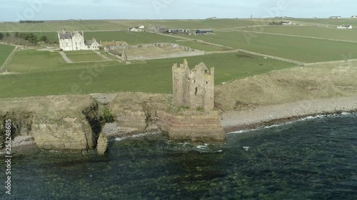 Aerial shot backing away from Keiss Castle out towards the sea on a sunny day, Caithness, Scotland photo