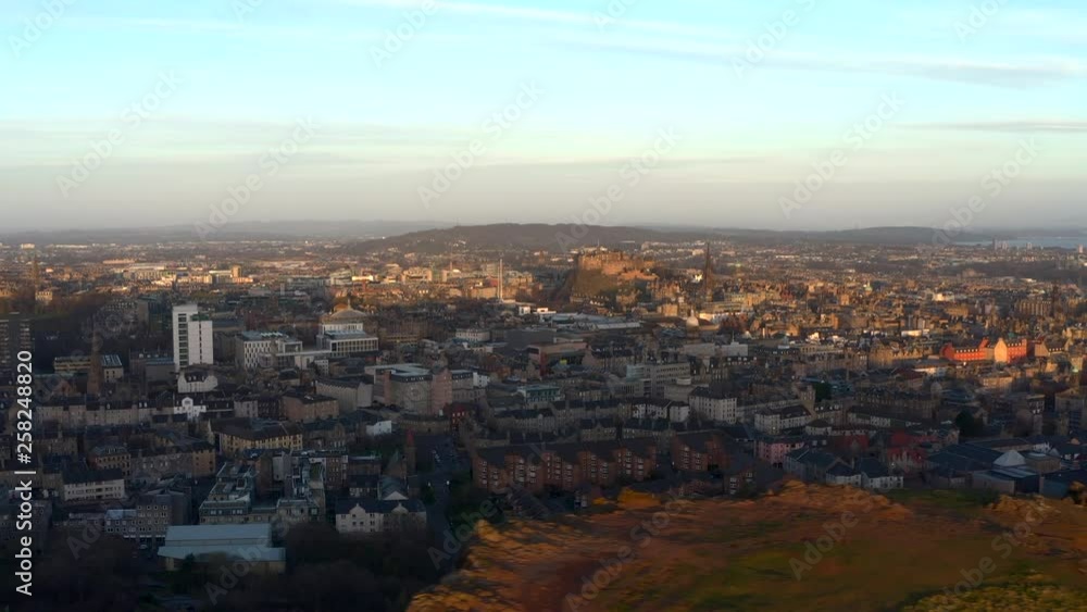 Track right over Salisbury Crags in Holyrood park with Edinburgh city below as dawn breaks, Scotland Track right over Salisbury Crags in Holyrood park with Edinburgh city below as dawn breaks, Scotland