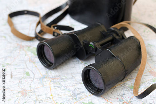 Black binoculars on the tourist map. This is an important equipment of researchers and tourists.