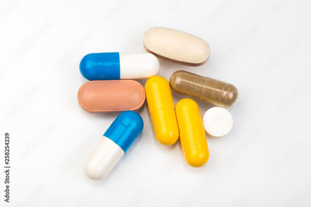 set of multi-colored tablets and capsules on a white background set of multi-colored tablets and capsules on a white background