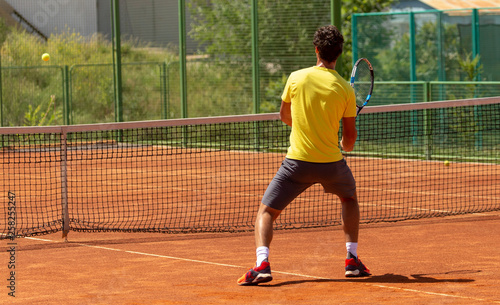 A man plays tennis on the court in the park © schankz