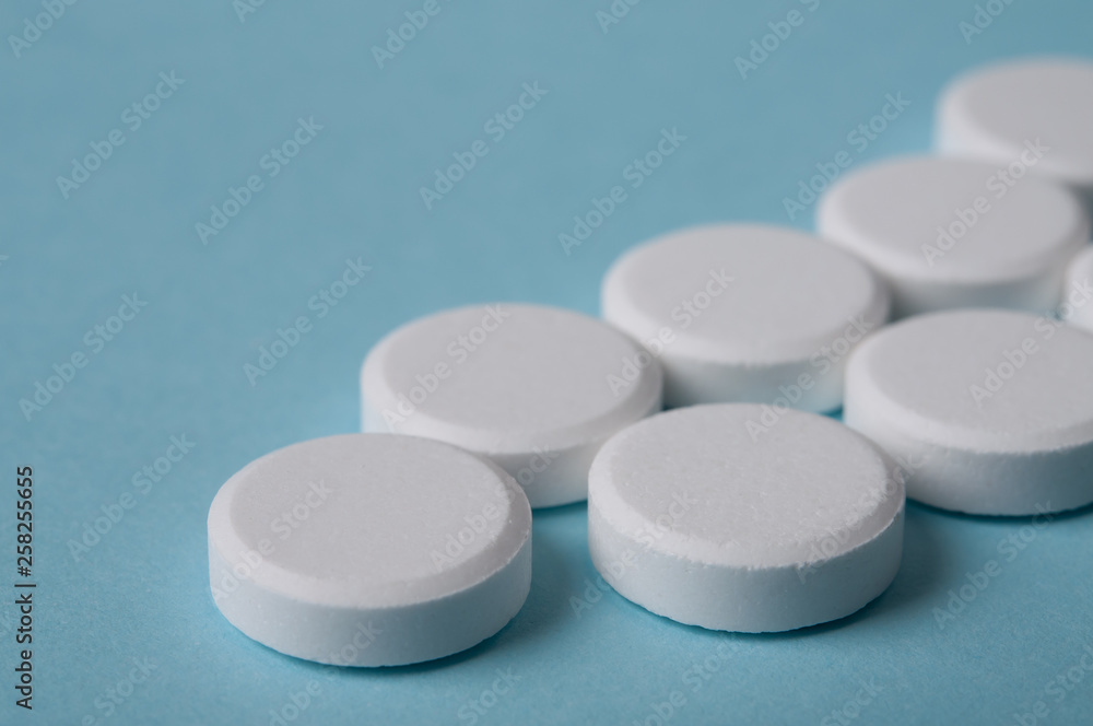 white pills closed up on blue background white pills closed up on blue background