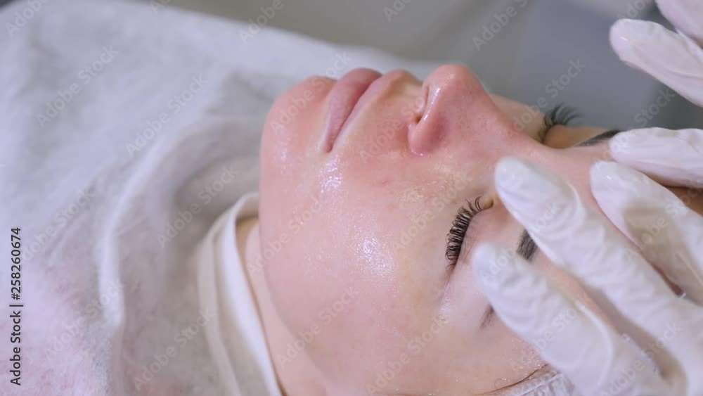 beautician smears on the face cream patient lying on the couch beautician smears on the face cream patient lying on the couch