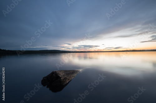 Fototapeta Naklejka Na Ścianę i Meble -  Rock in a calm lake in sweden at sunset