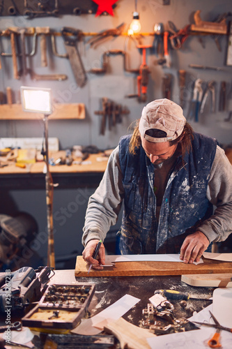 Male carpenter working on old wood in a retro vintage workshop.