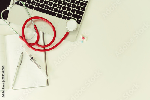 Medical healthcare backgrounds flat lay objects with copy space. Doctor stethoscope, medicine, laptop computer and notebook on white office table. photo