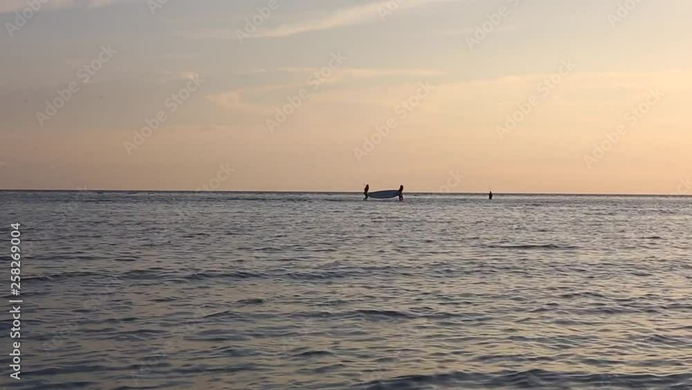 Two men carring puddle surfboard from the sea on sunset. Two men carring puddle surfboard from the sea on sunset.