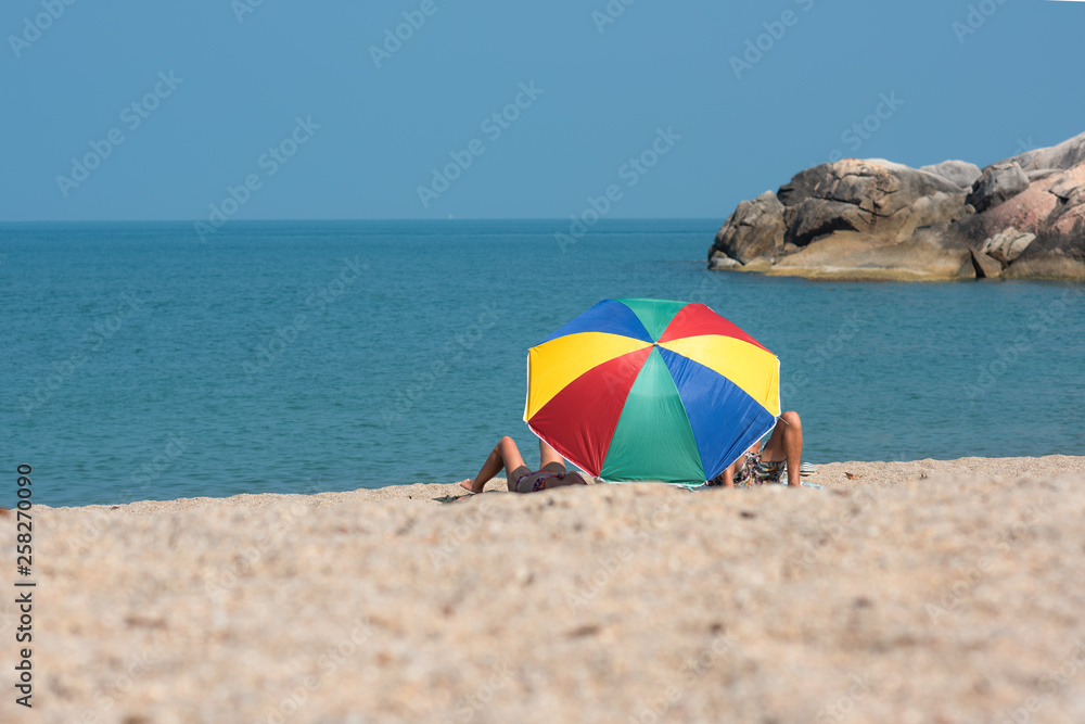 multicolor beach parasol gamp umbrella pin on the sea beach at sunlight