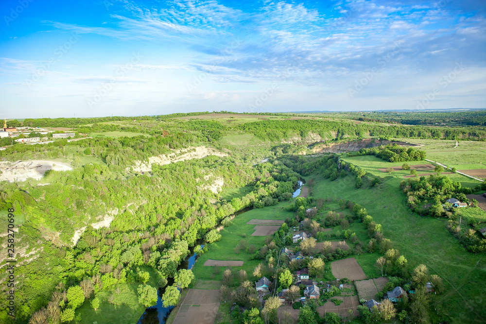 Fototapeta premium Aerial view of green fields, farms and gardens by blue sky