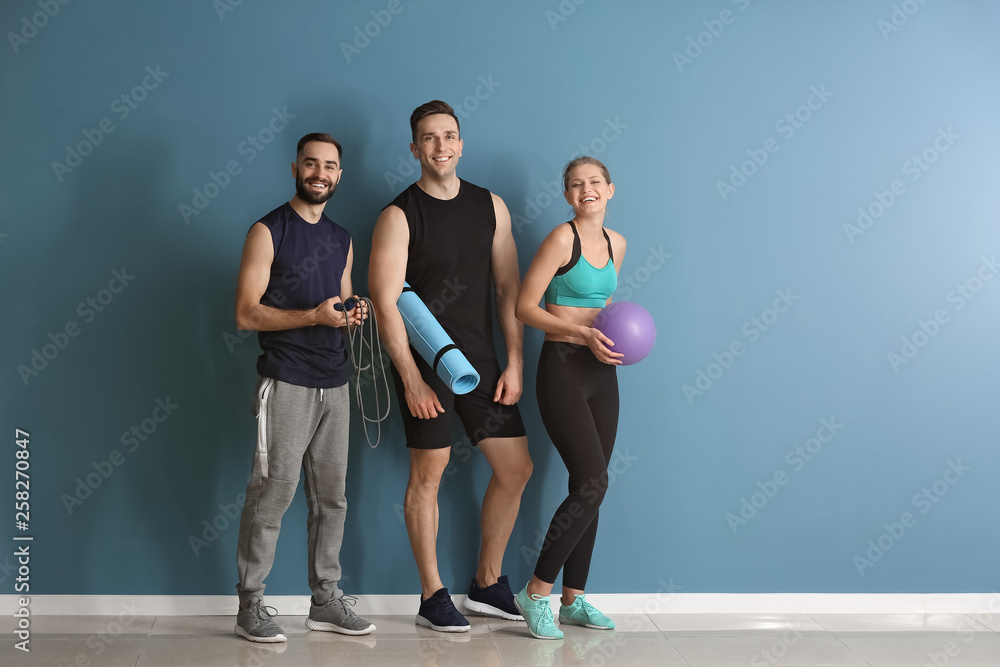 Fototapeta premium Sporty young people near color wall