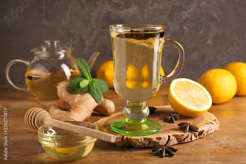 Cup of tasty drink with lemon, ginger and honey on wooden table