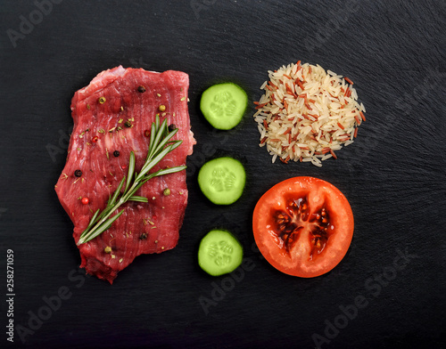 Foog set with a fresh raw piece of beefsteak with rice, vegetable and spices