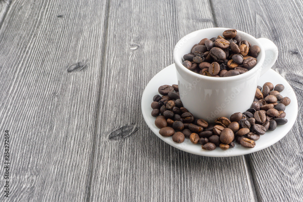 Fototapeta premium Coffee cup and coffee beans on wooden background. Top view and selective focus