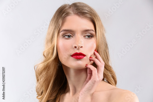 Beautiful young woman with bright makeup on light background