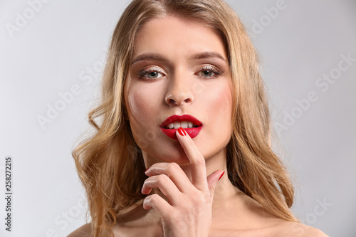 Beautiful young woman with bright makeup on light background