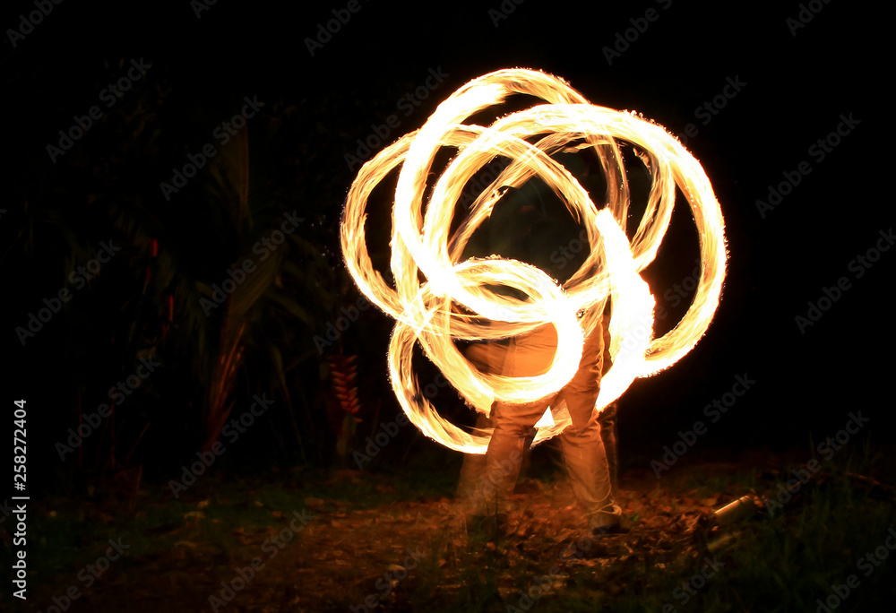 A fire dancer spins fire on balls with chains (poi) on the beach. A fire dancer spins fire on balls with chains (poi) on the beach.