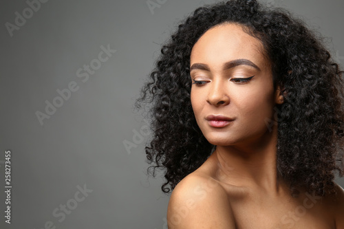 Portrait of beautiful African-American woman on grey background