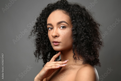 Portrait of beautiful African-American woman on grey background