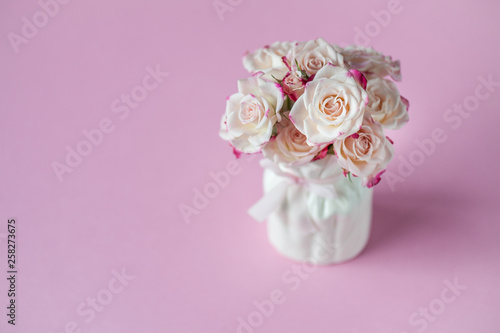 Coral roses in vase on pink background. Greeting card. Happy Mother's Day, Women's Day or Birthday. Minimalism, selective focus, place for text.