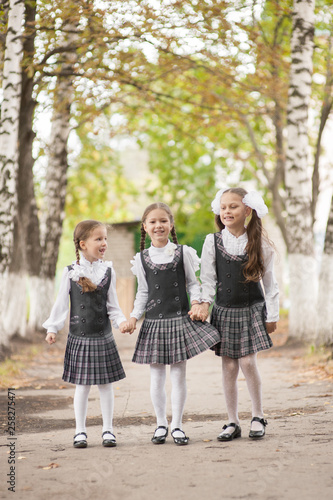 Wallpaper Mural Smiling young children in a school uniform jumping on the road in the park at the day time. Torontodigital.ca