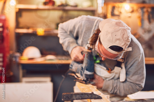 Male carpenter working on old wood in a retro vintage workshop.