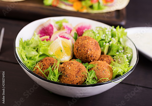 Falafel and fresh vegetables. Buddha bowl. Middle eastern or arabic dishes on a dark background. Halal food.