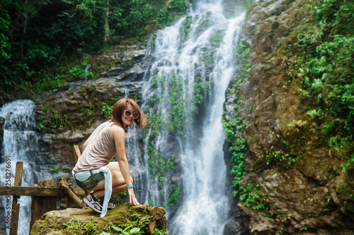 Young woman enjoying tropical waterfall in Asia