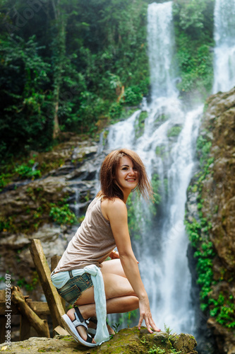 Young woman enjoying natural bathing by the Tamaraw waterfall on background.