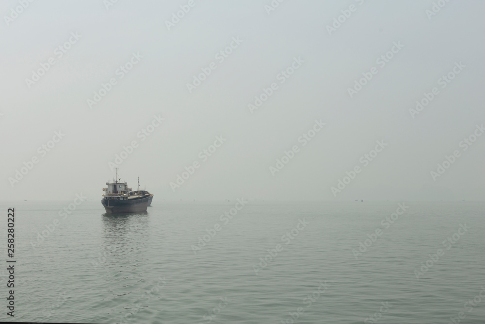 Merchant ship in the haze of Halong Bay