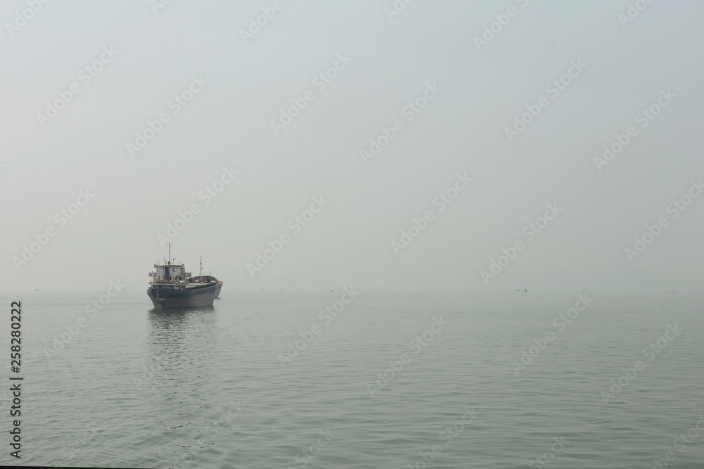 Merchant ship in the haze of Halong Bay Merchant ship in the haze of Halong Bay