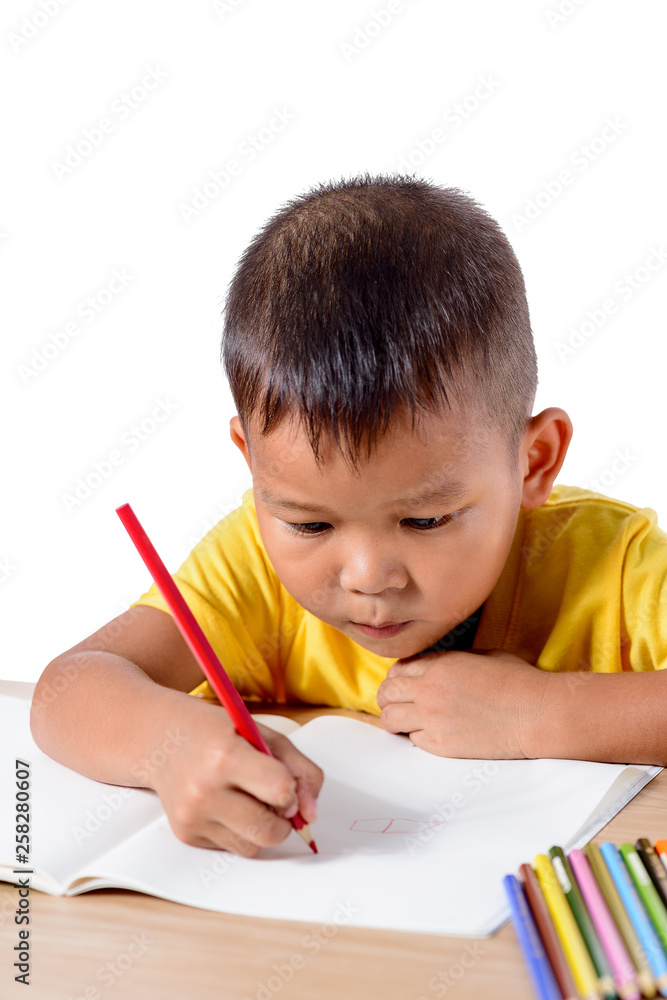Cute cheerful child drawing using color pencil while sitting at table isolated on white background Cute cheerful child drawing using color pencil while sitting at table isolated on white background