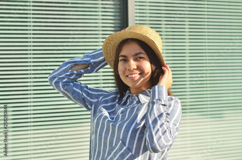 Asian young girl is walking down the street dressed, in the hat and blue striped shirt