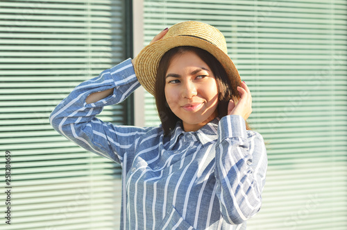 Asian young girl is walking down the street dressed, in the hat and blue striped shirt